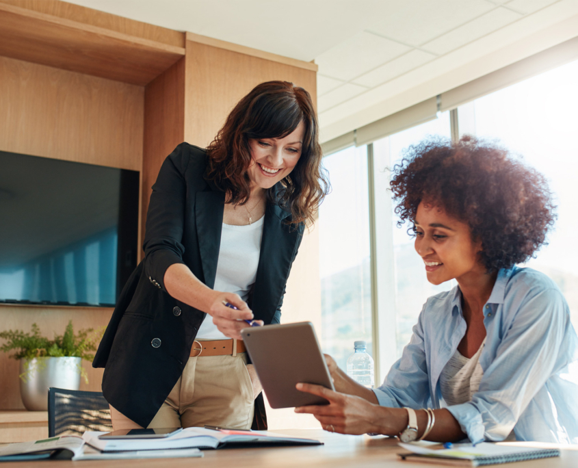 2 business women in office meeting with tablet