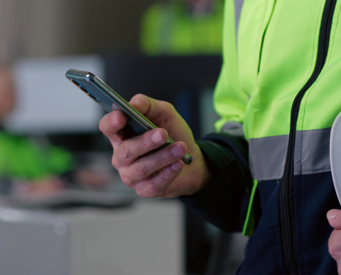 Cropped shot of builder chat on smartphone holding hardhat