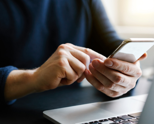 Man with a finger on the screen using a mobile phone in the office